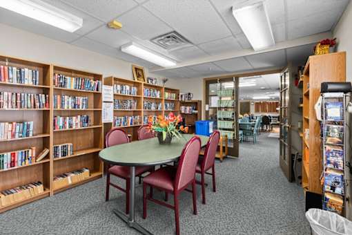 A library with a round table and chairs in the middle of the room.