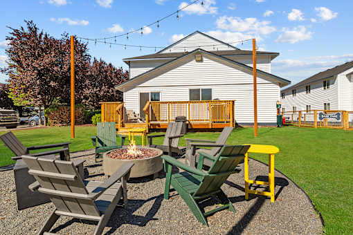 A fire pit surrounded by chairs in a backyard.