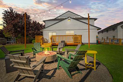 A fire pit surrounded by chairs in a backyard.