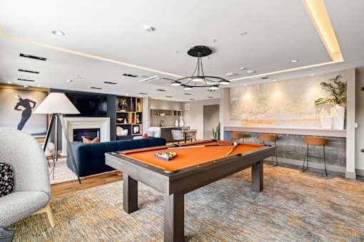 A billiard table is in the middle of a room with a blue couch and a fireplace.