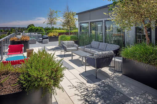 A patio with a red chair and a grey sofa.