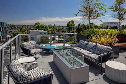 A patio with a glass table surrounded by chairs and couches.