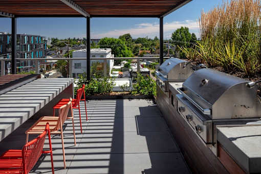 A patio with red chairs and a grill.