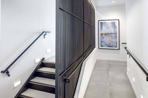 A staircase with a metal railing and steps leading up to a picture.