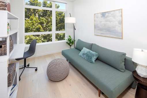 A living room with a green couch and a large window.
