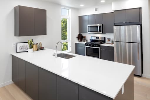 A modern kitchen with a white countertop and stainless steel appliances.