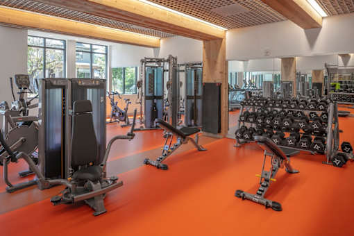 A gym with orange flooring and various exercise equipment.