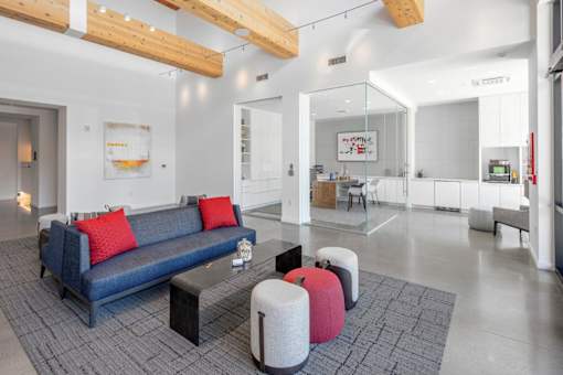 A modern living room with a blue couch and red pillows.