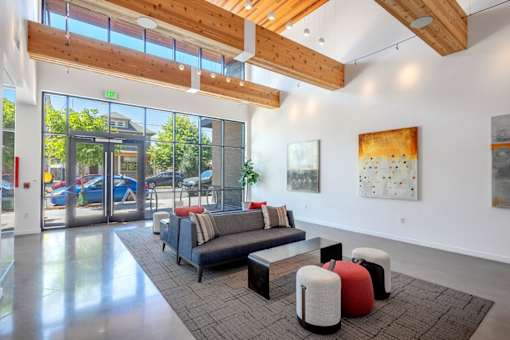 A modern living room with a couch, ottoman, and artwork on the wall.