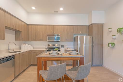 A modern kitchen with a dining table set for two.
