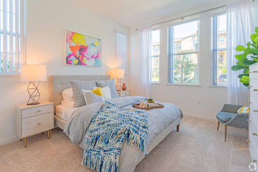 A bedroom with a bed, a chair, and a painting on the wall.
