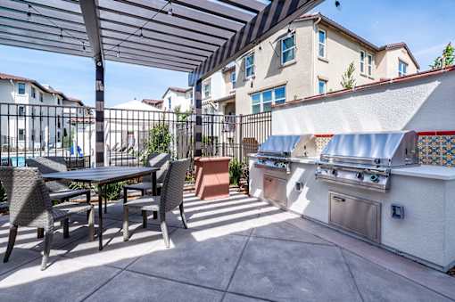 A patio with a table and chairs and a grill.