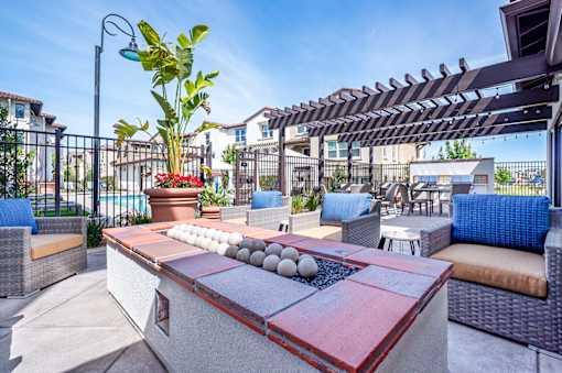 A patio with a table, chairs, and a potted plant.