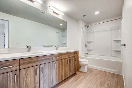 A modern bathroom with wooden cabinets and a white bathtub.