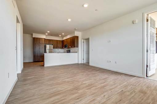 A spacious kitchen with wooden floors and white walls.