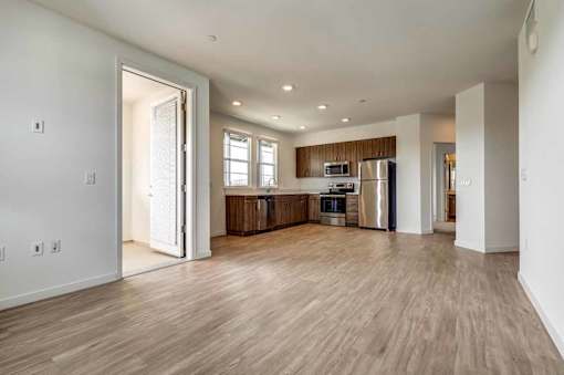 A kitchen with a refrigerator, oven, and sink is visible through an open door.