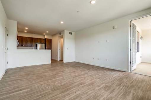 A large empty room with wooden flooring and white walls.