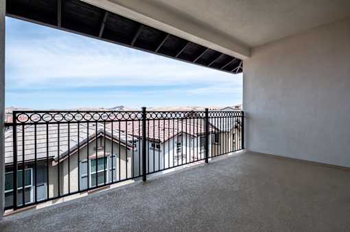 A balcony with a black railing and a view of houses and trees.
