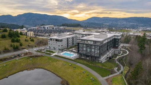 an aerial view of a building with a pool and mountains in the background