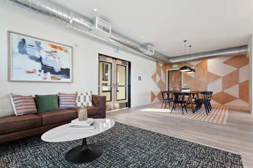 A living room with a brown couch, a white coffee table, and a painting on the wall.