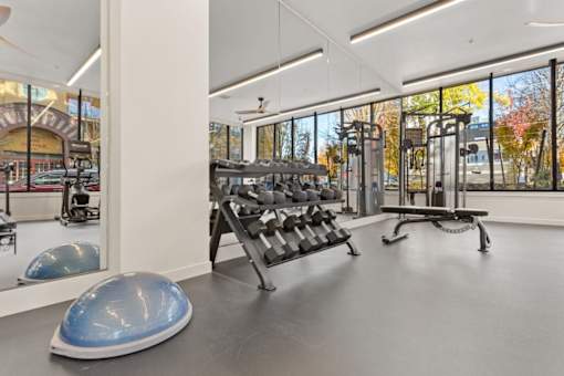 A gym with a variety of equipment including a rowing machine, a bench press, and a leg press.