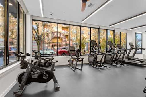A gym with a row of treadmills and stationary bikes.
