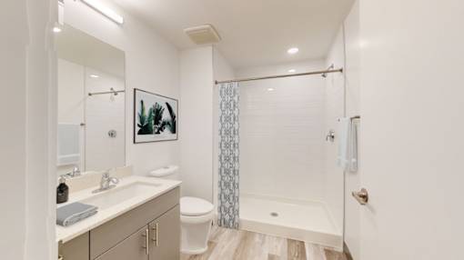 A white bathroom with a toilet, sink, and shower.