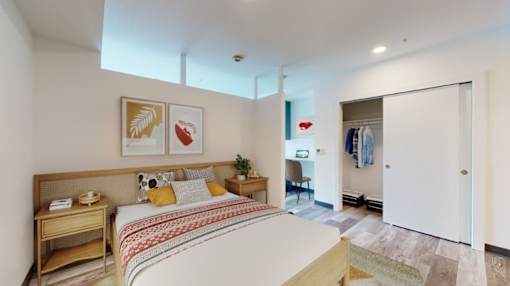 A bedroom with a bed, nightstand, and chair.