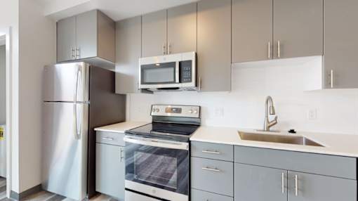 A modern kitchen with a stainless steel refrigerator, microwave, and dishwasher.