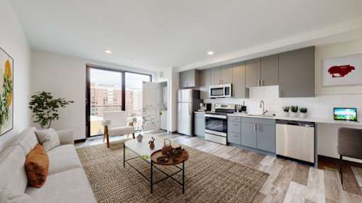 A modern kitchen and living room with a large window and a view of the city.