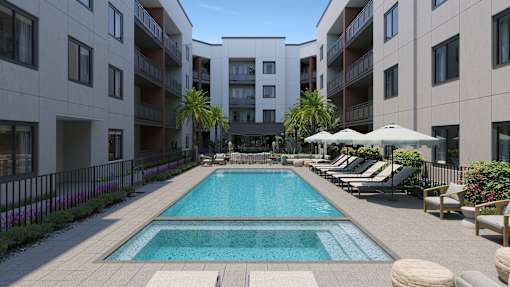 A large swimming pool in the middle of a courtyard surrounded by lounge chairs and umbrellas.