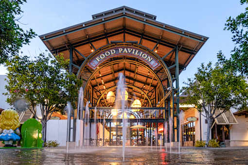 A fountain in front of a building with the words Food Pavilion on it.