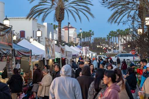 A busy street market with people walking around and stalls set up.