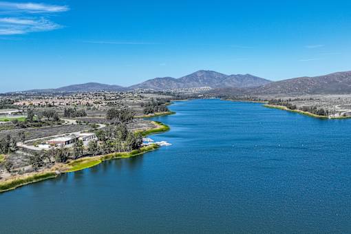 A large body of water surrounded by greenery and mountains.