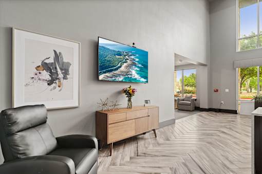 A living room with a black leather chair, a wooden dresser, and a painting on the wall.