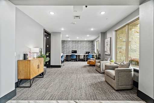 A modern office space with a grey carpet and a variety of seating options.
