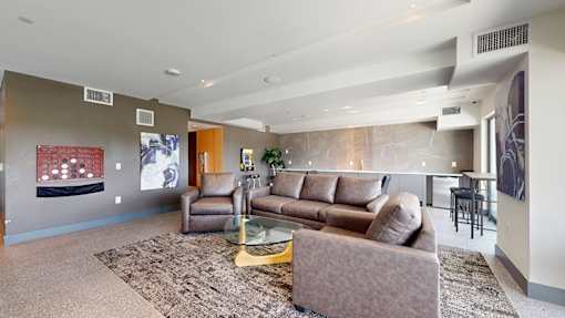 A living room with a brown couch and a glass coffee table.