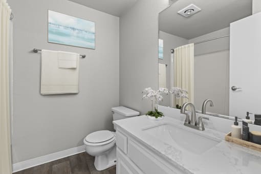 a white bathroom with a large mirror and a toilet and sink