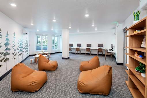 A room with bean bag chairs and a tree mural on the wall.