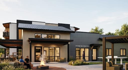 A modern fitness center with a fire pit in front.