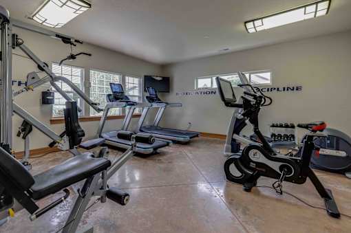 A gym with a row of treadmills and a row of stationary bikes.