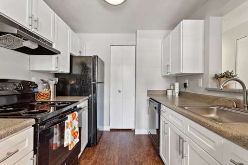 A kitchen with black appliances and white cabinets.