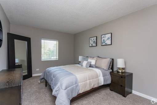 A bedroom with a bed, nightstand, and two pictures on the wall.