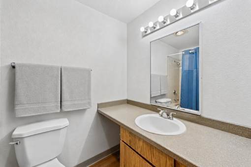 A bathroom with a toilet, sink, mirror, and towel.