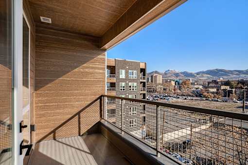 A balcony with a view of a parking lot and buildings.