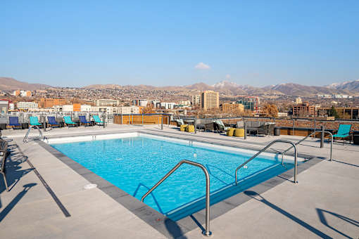 A swimming pool on a rooftop with mountains in the background.