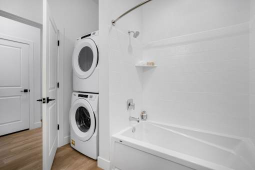 A white bathroom with a washing machine in the corner.