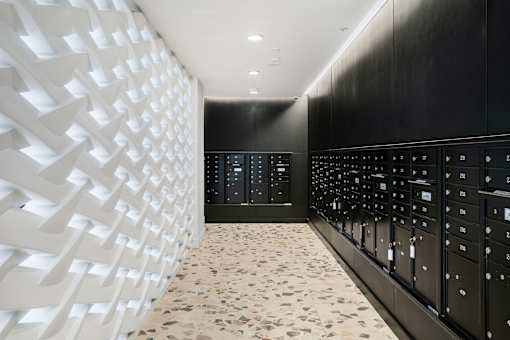 A hallway with a white patterned wall and a black wall with a number of buttons.