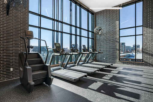 A gym with treadmills, elliptical machines, and a weight bench.
