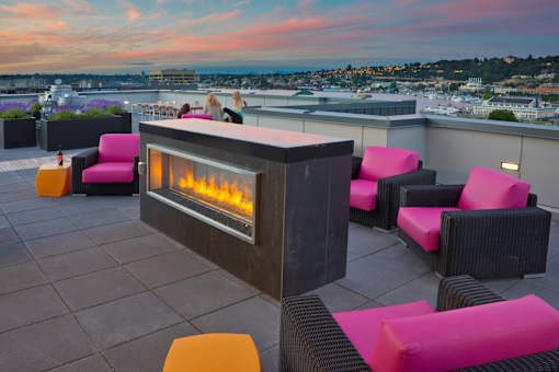 A modern outdoor seating area with a fireplace on a rooftop.